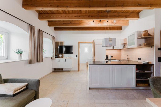 Helle, moderne Küche mit Holzbalken, Sofa und Fenster für natürliche Beleuchtung.